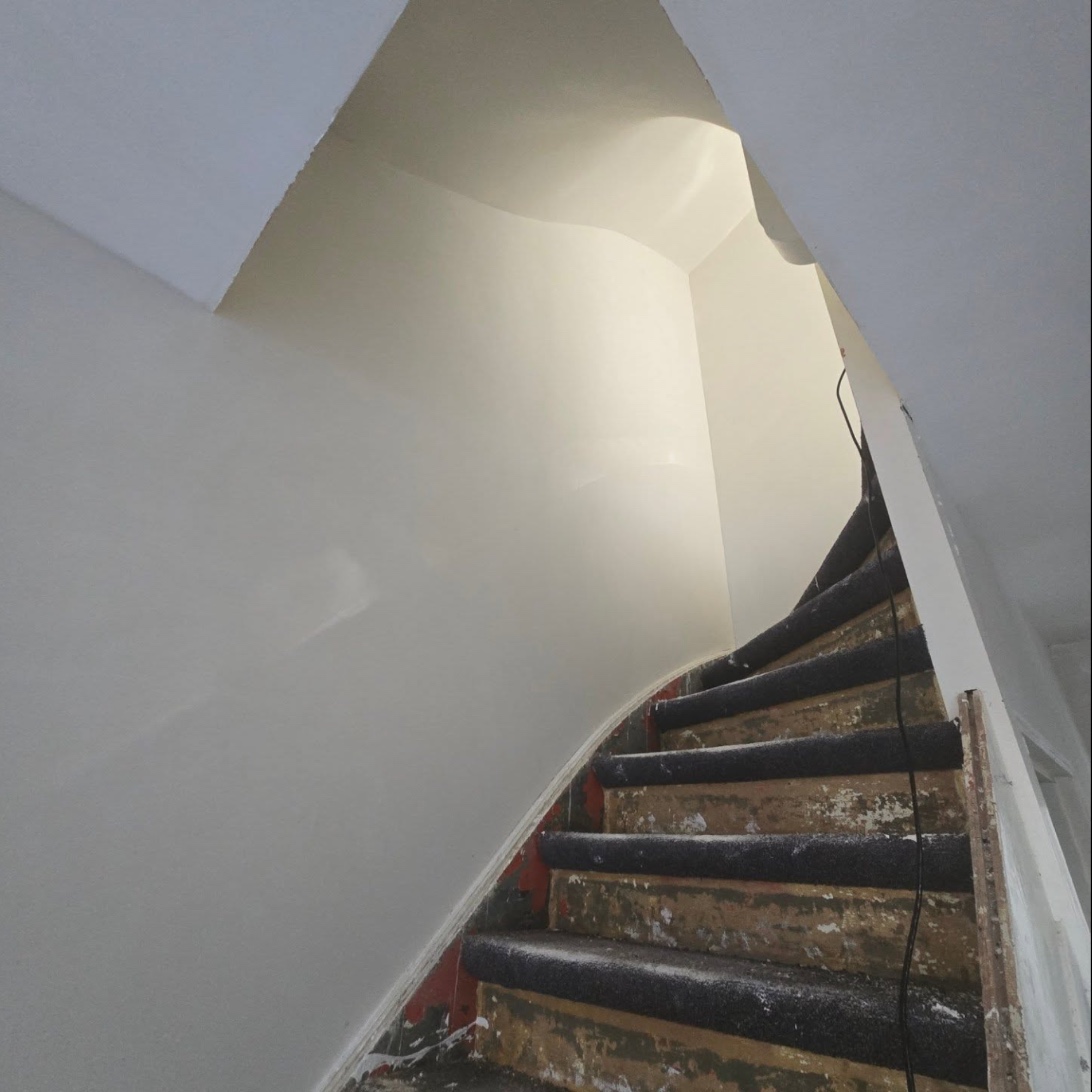 Curved stair wall in smooth plaster along a staircase