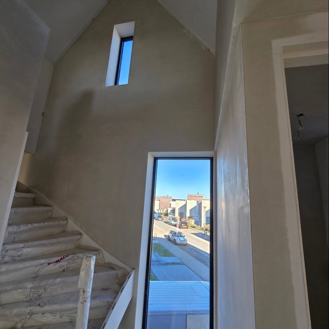 Stairwell with a high plastered wall and a narrow window