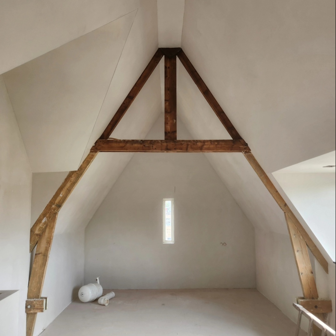 High attic with an A-frame timber truss and smoothly plastered walls
