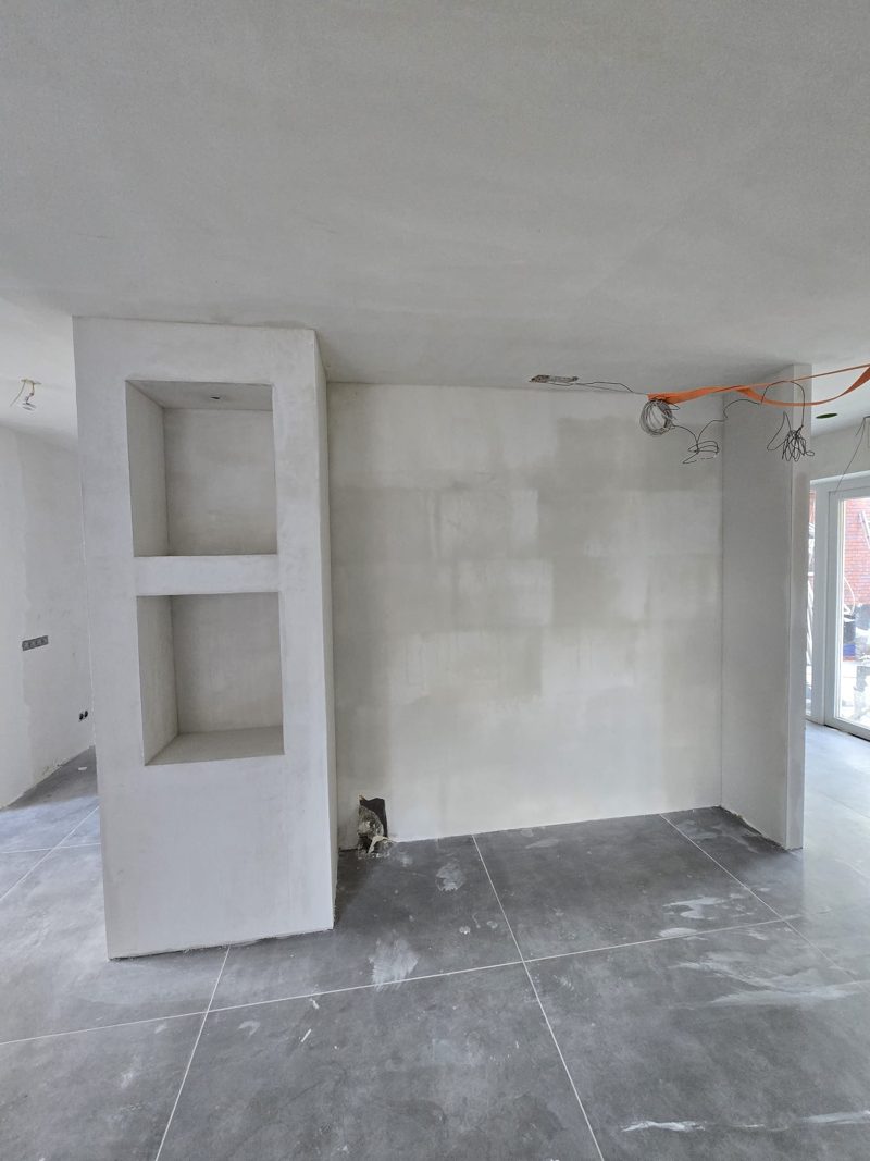 Na: dezelfde ombouw met nissen en de wand ernaast glad gestuct