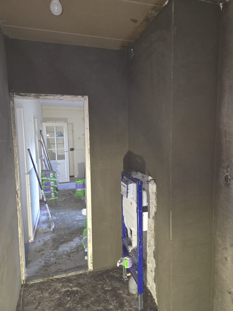 Bathroom with a dark grey coat of plaster on the walls, the built-in toilet cistern on the right