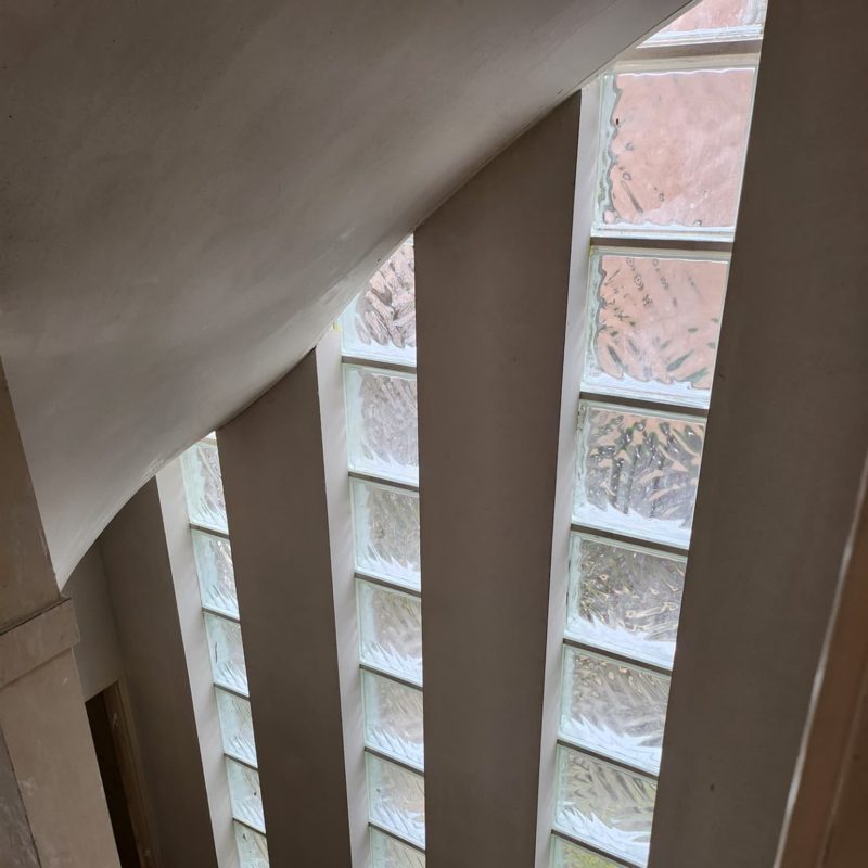 Stairwell with a curved plastered wall and strips of glass blocks