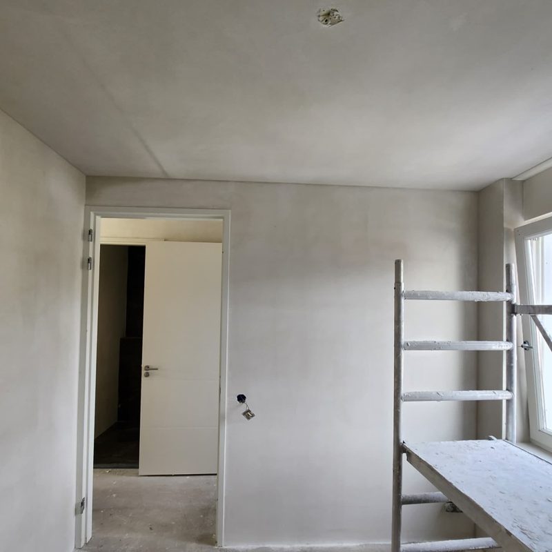 After: the same room with smooth white plastered walls and ceiling, a mobile scaffold by the window